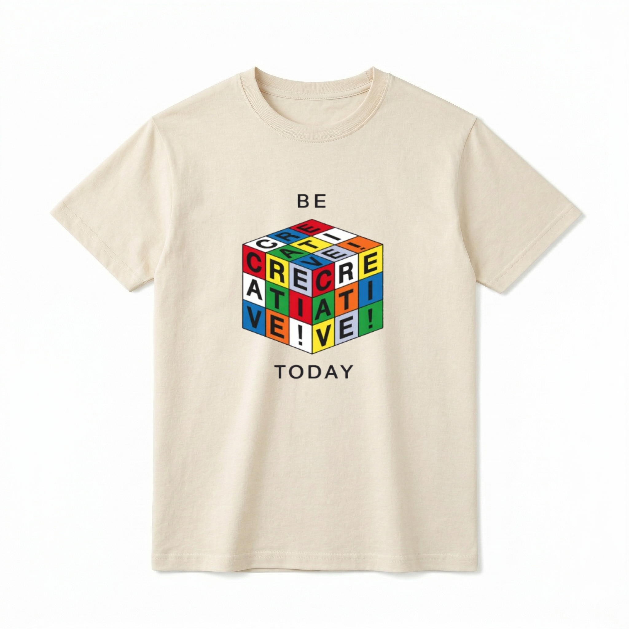 A flat lay of a short-sleeve t-shirt. The center chest features a graphic of a 3D puzzle cube with brightly colored grid squares in red, blue, green, yellow, orange, and white. The black letters across the visible grids spell out "CREATIVE!". Above the cube is the text "BE" and below the cube is the text "TODAY" in a simple, modern black font.